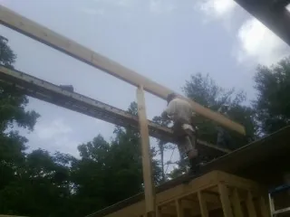 Carpenter setting a ridge beam over a new addition frame — Ice Dam Removal by Roofing Brothers in Mastic