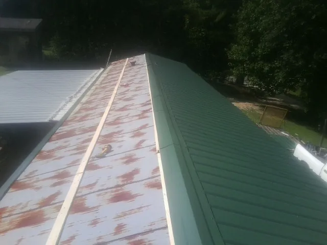 Old rusted panels beside newly installed green metal roofing — Wind Damage Roof Repair by Roofing Brothers in Mastic
