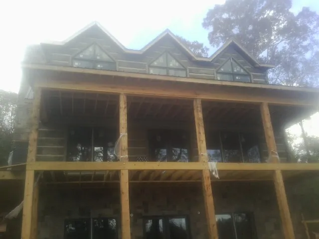 Dormers and porch framing on a large log home under construction — Roof Coating work by our crew in Mastic