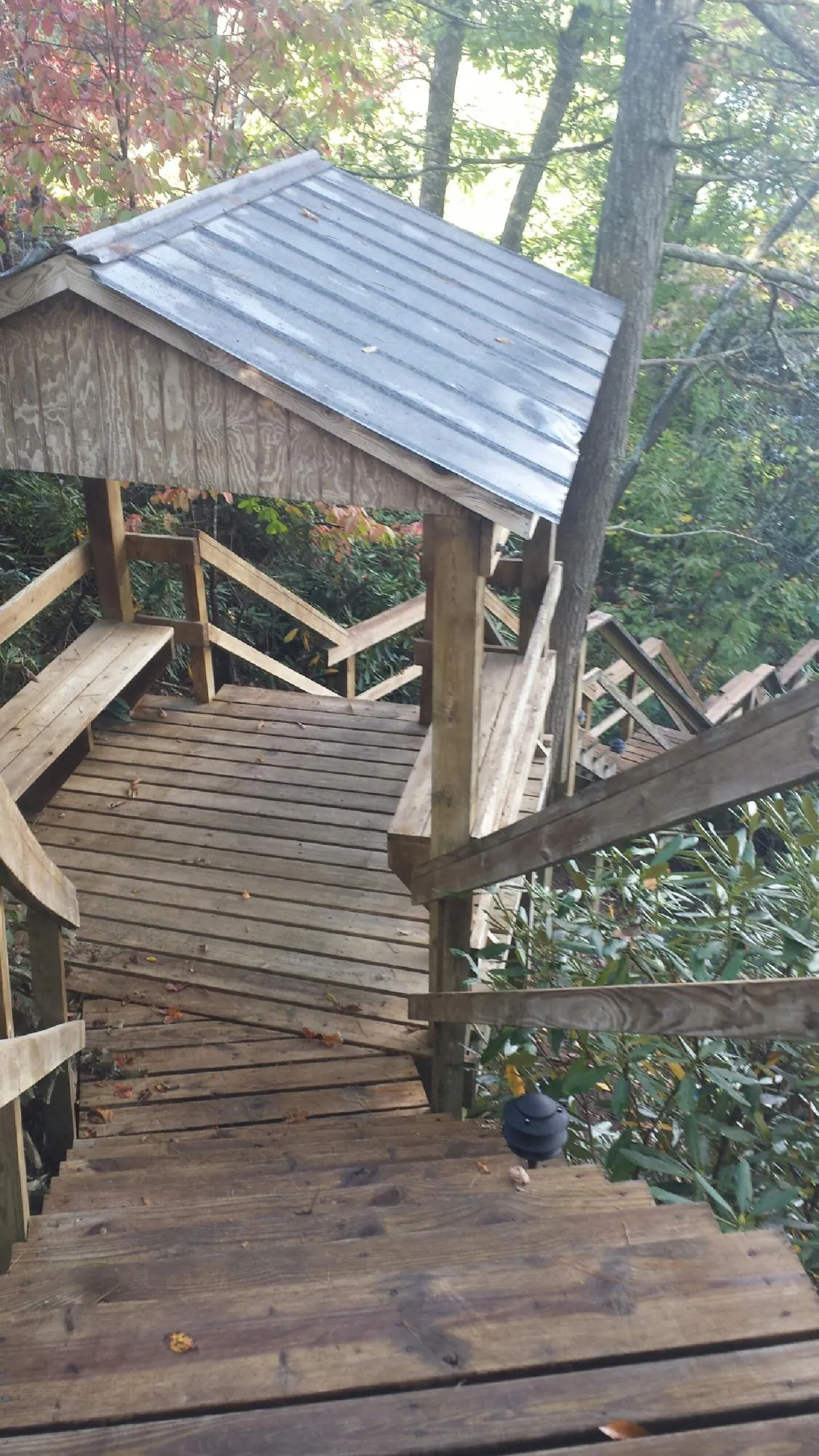 Metal roofed shelter over wooden steps on a wooded walkway — Skylight Repair & Installation work by our crew in Mastic